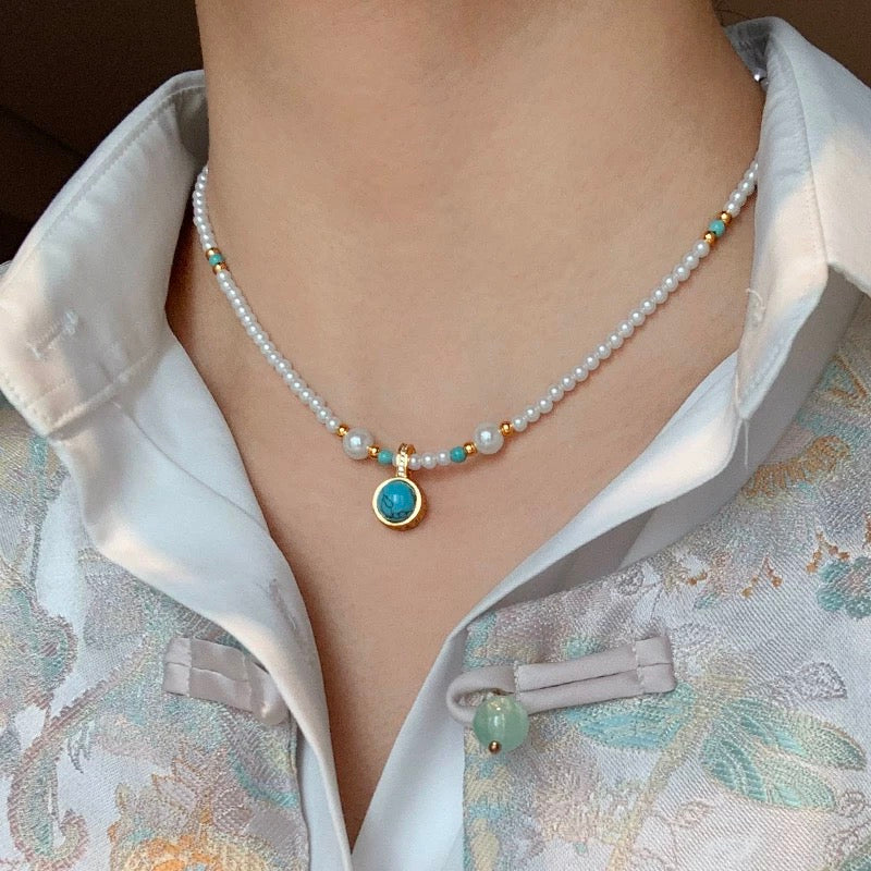 Close-up of a baby pearl necklace with 3–4mm freshwater pearls and a gold-filled charm pendant featuring a universal clasp.
