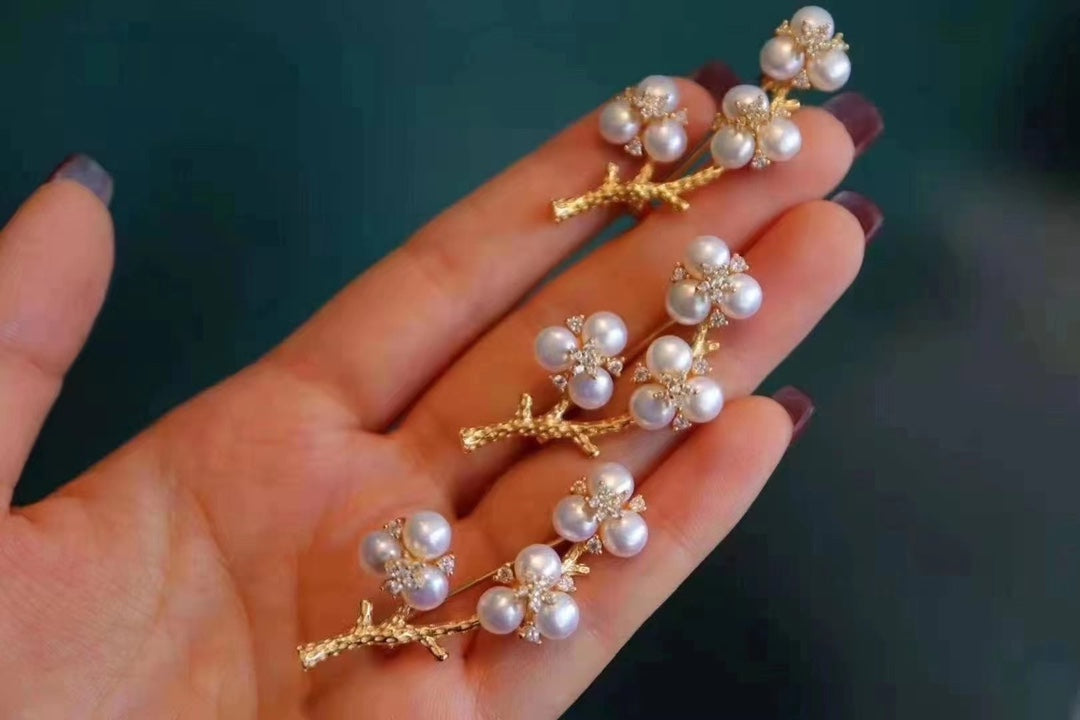 Gold-plated brooch inspired by Chinese plum blossom design with white freshwater pearls, symbolizing elegance and tradition.