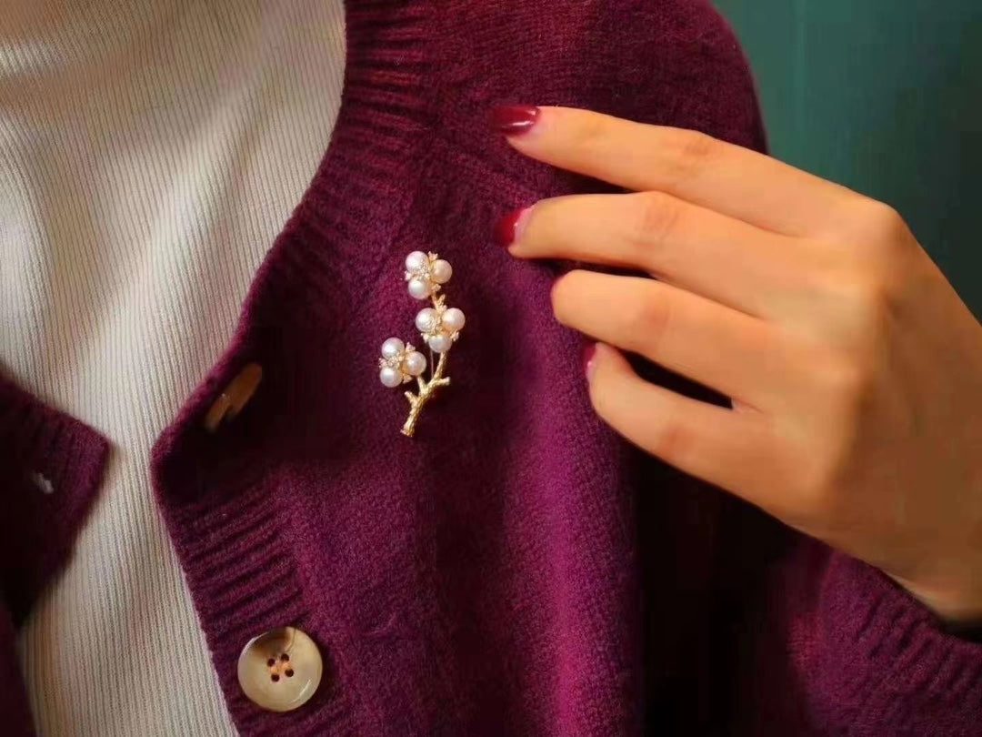 Gold-plated brooch inspired by Chinese plum blossom design with white freshwater pearls, symbolizing elegance and tradition.
