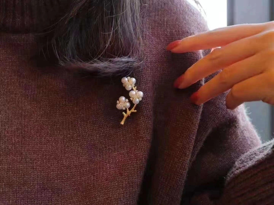 Gold-plated brooch inspired by Chinese plum blossom design with white freshwater pearls, symbolizing elegance and tradition.