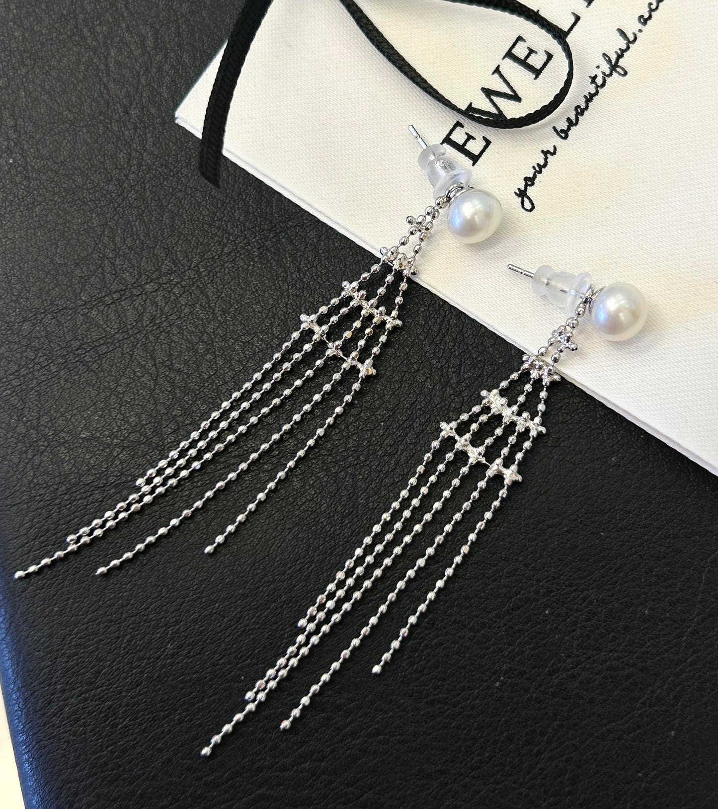 Asymmetric tassel earrings with 7–8mm freshwater pearls and sterling silver posts, featuring a dewdrop-inspired flowing design.