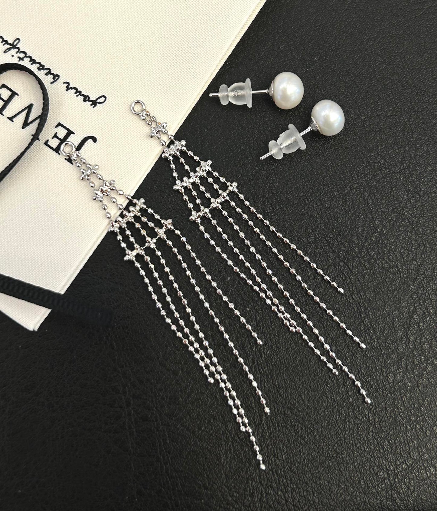 Asymmetric tassel earrings with 7–8mm freshwater pearls and sterling silver posts, featuring a dewdrop-inspired flowing design.