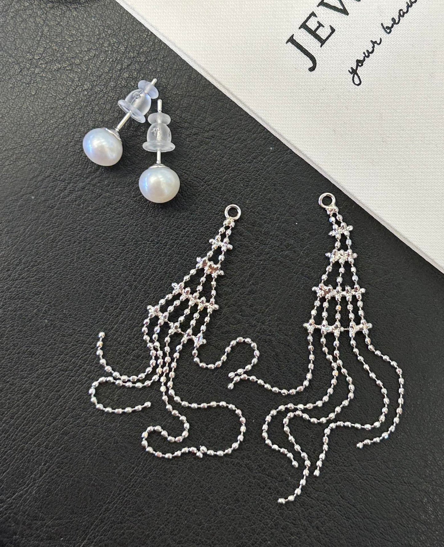Asymmetric tassel earrings with 7–8mm freshwater pearls and sterling silver posts, featuring a dewdrop-inspired flowing design.