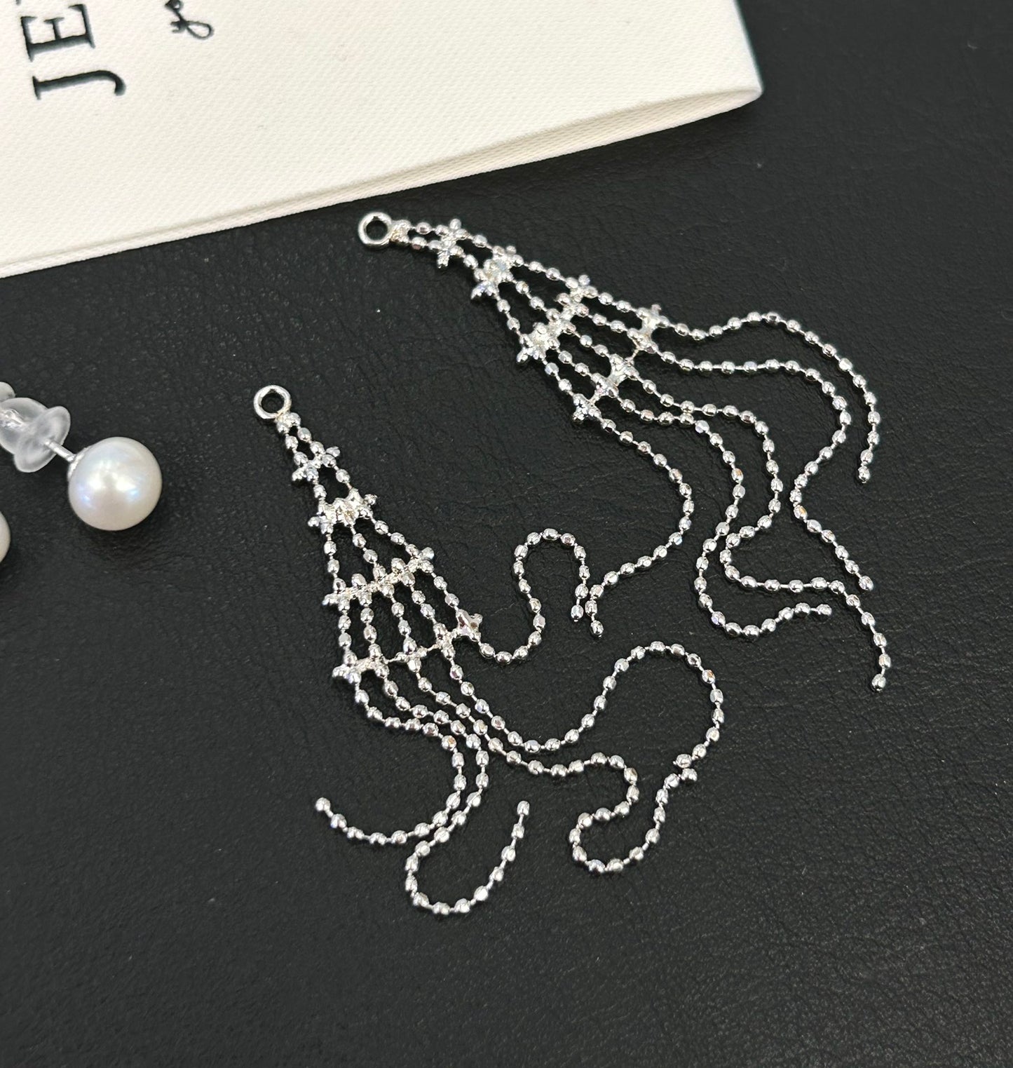 Asymmetric tassel earrings with 7–8mm freshwater pearls and sterling silver posts, featuring a dewdrop-inspired flowing design.