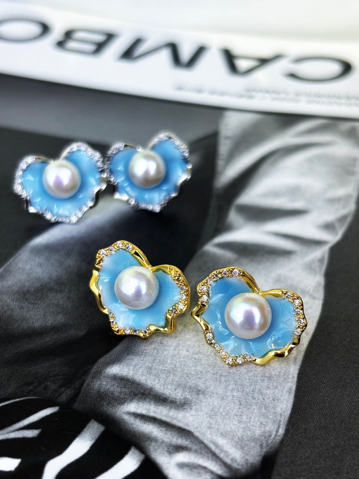 A pair of glacier blue enamel stud earrings featuring 8mm natural freshwater pearls and sterling silver posts.