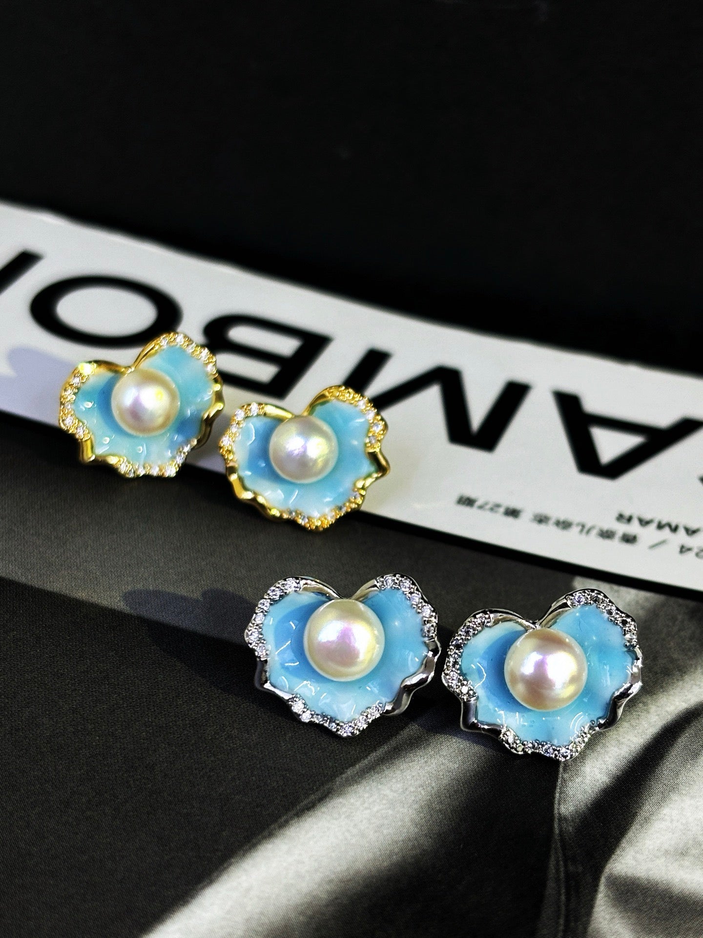A pair of glacier blue enamel stud earrings featuring 8mm natural freshwater pearls and sterling silver posts.