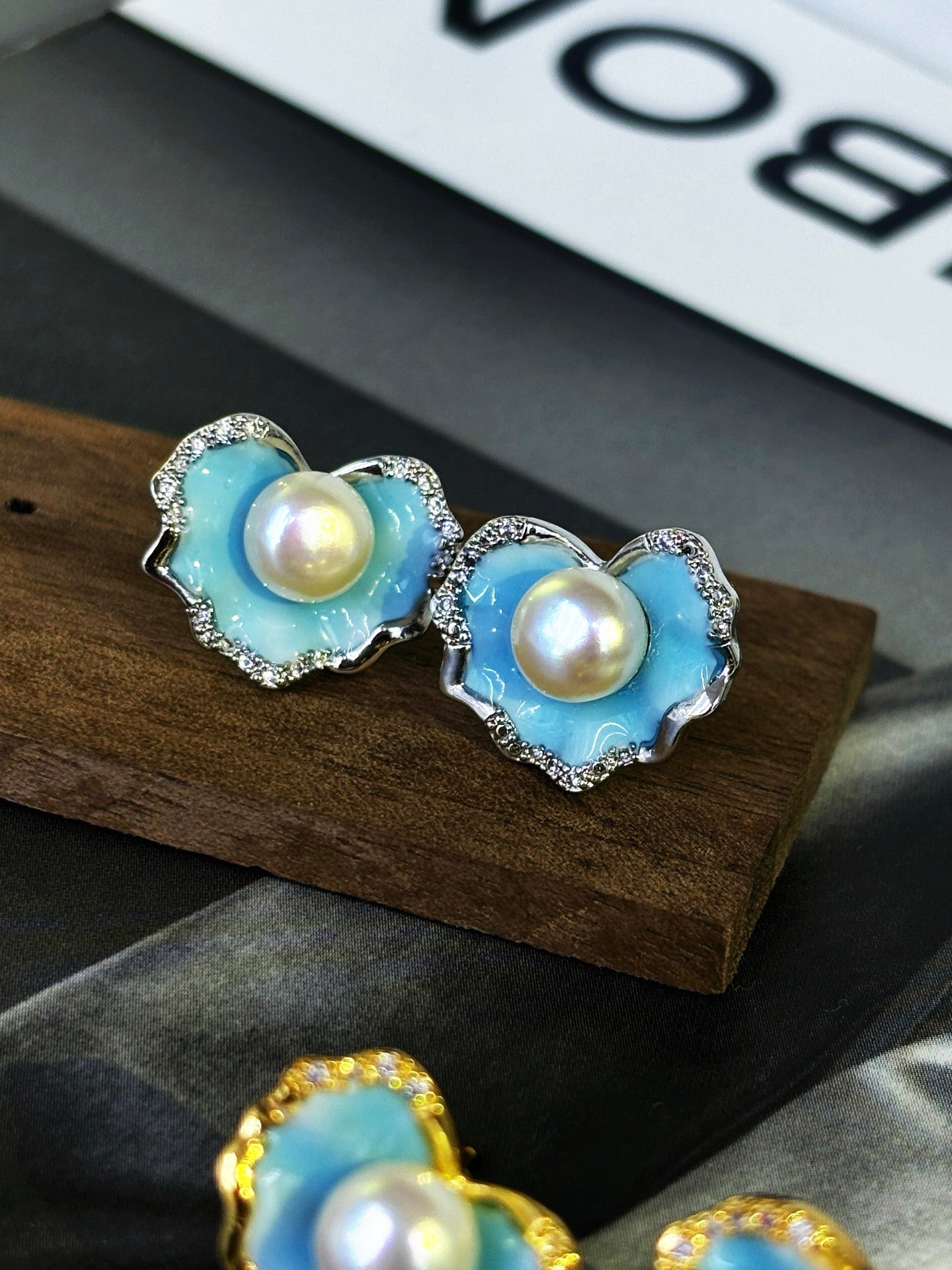 A pair of glacier blue enamel stud earrings featuring 8mm natural freshwater pearls and sterling silver posts.
