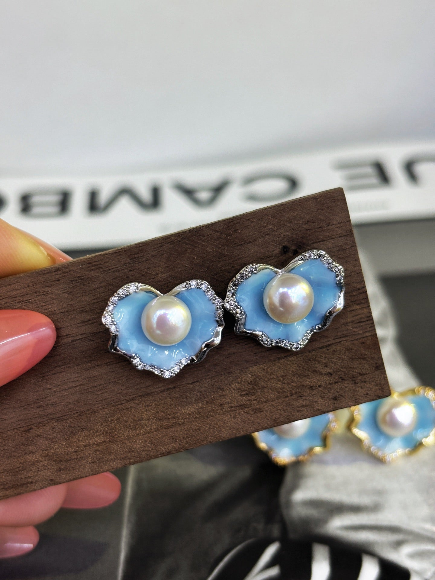 A pair of glacier blue enamel stud earrings featuring 8mm natural freshwater pearls and sterling silver posts.