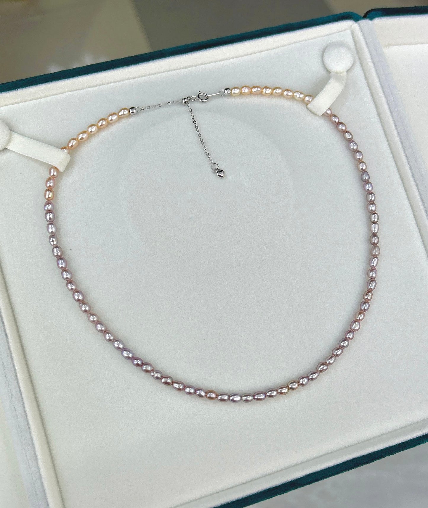 Gradient necklace featuring 3–4mm freshwater pearls fading from orange to purple, with sterling silver adjustable clasp.