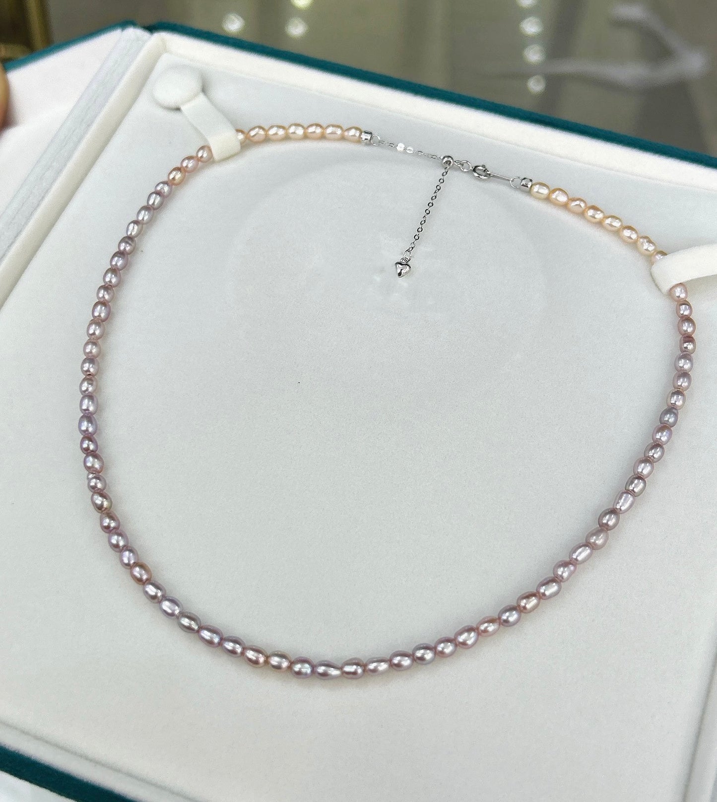 Gradient necklace featuring 3–4mm freshwater pearls fading from orange to purple, with sterling silver adjustable clasp.