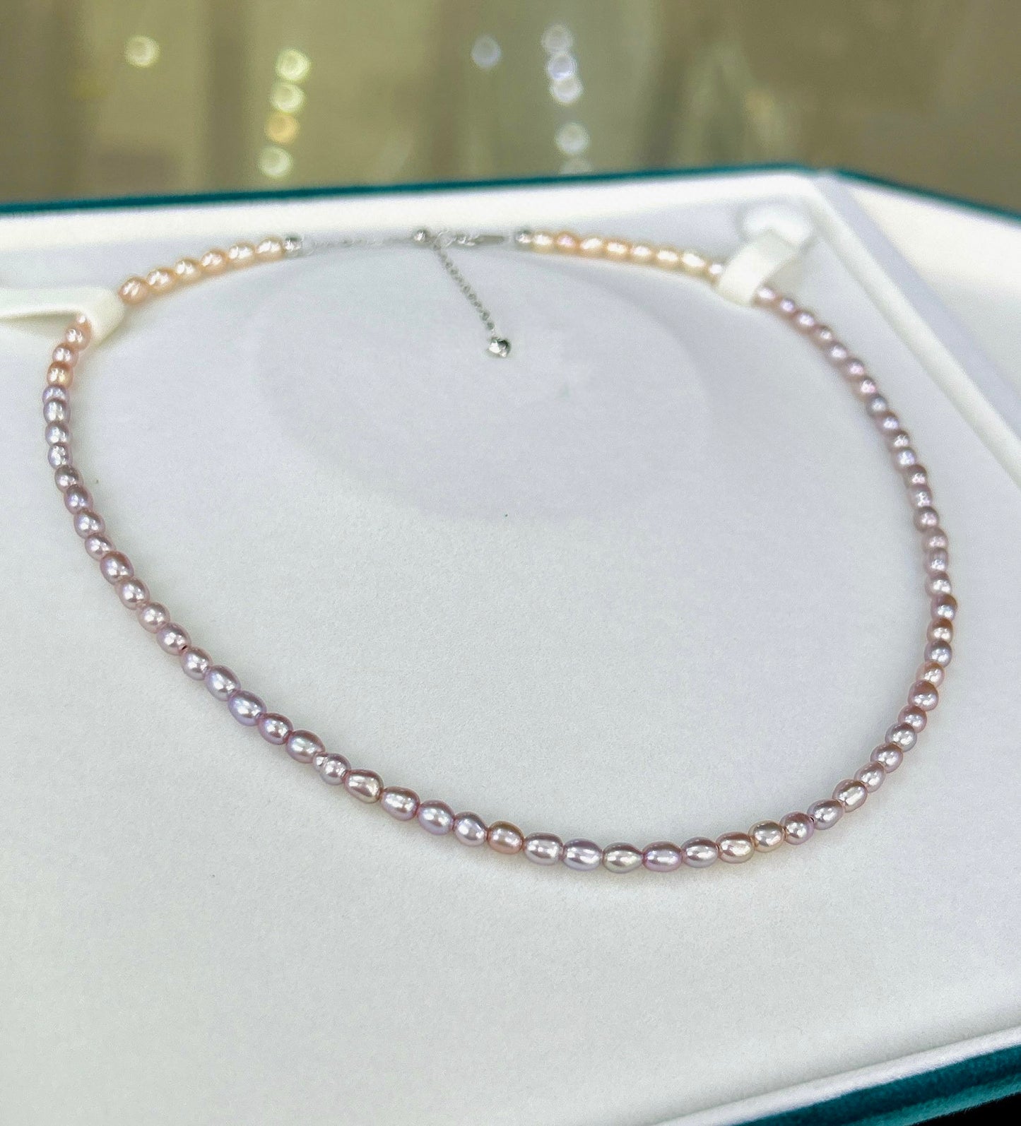 Gradient necklace featuring 3–4mm freshwater pearls fading from orange to purple, with sterling silver adjustable clasp.