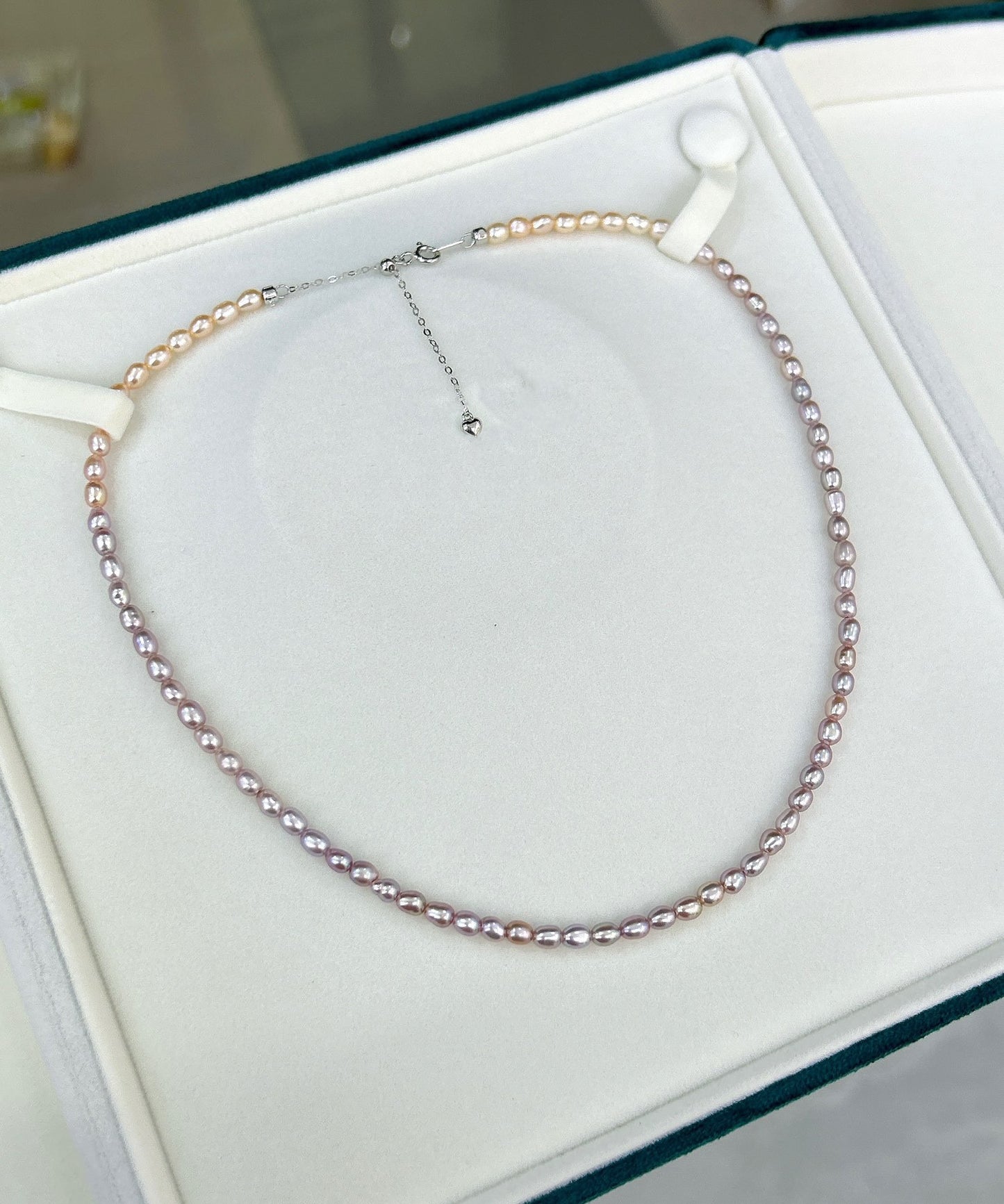 Gradient necklace featuring 3–4mm freshwater pearls fading from orange to purple, with sterling silver adjustable clasp.