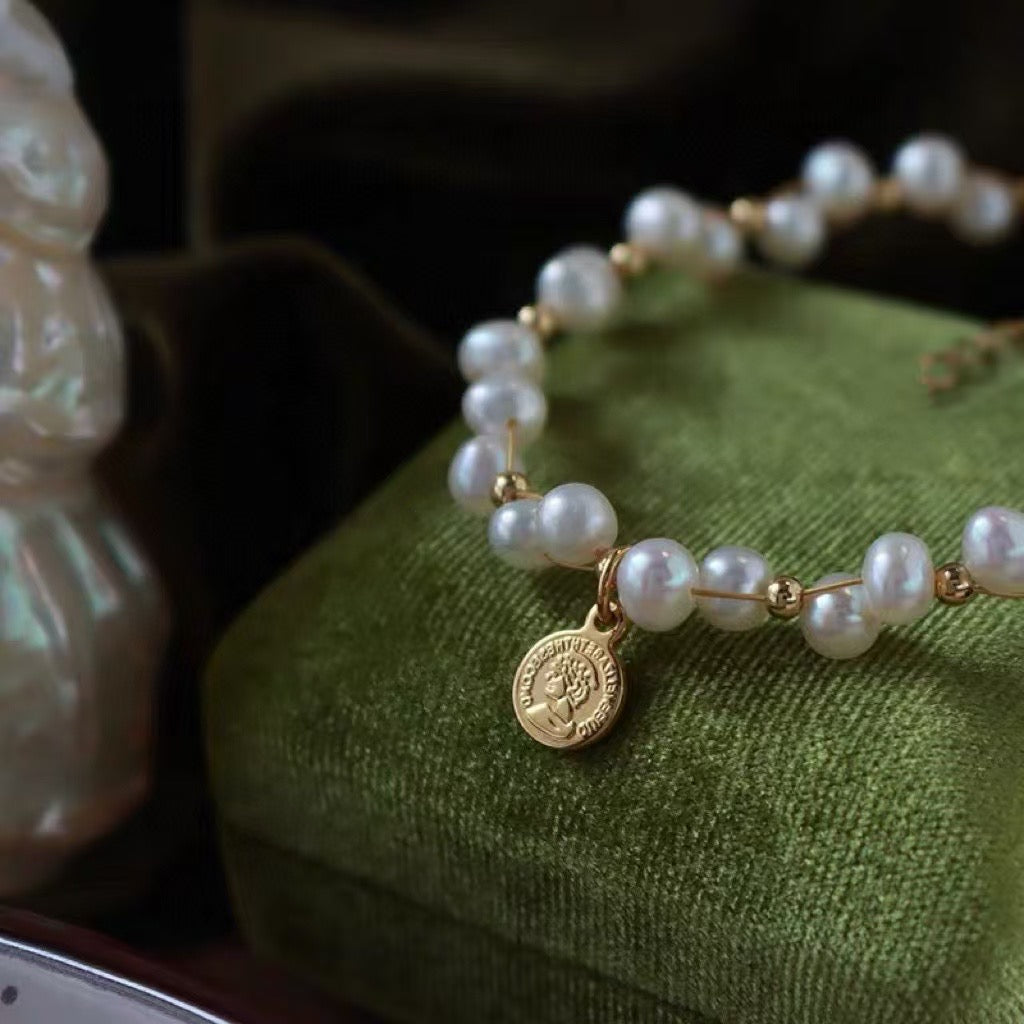 Minimalist freshwater pearl bracelet with round charm and adjustable Japanese woven cord.