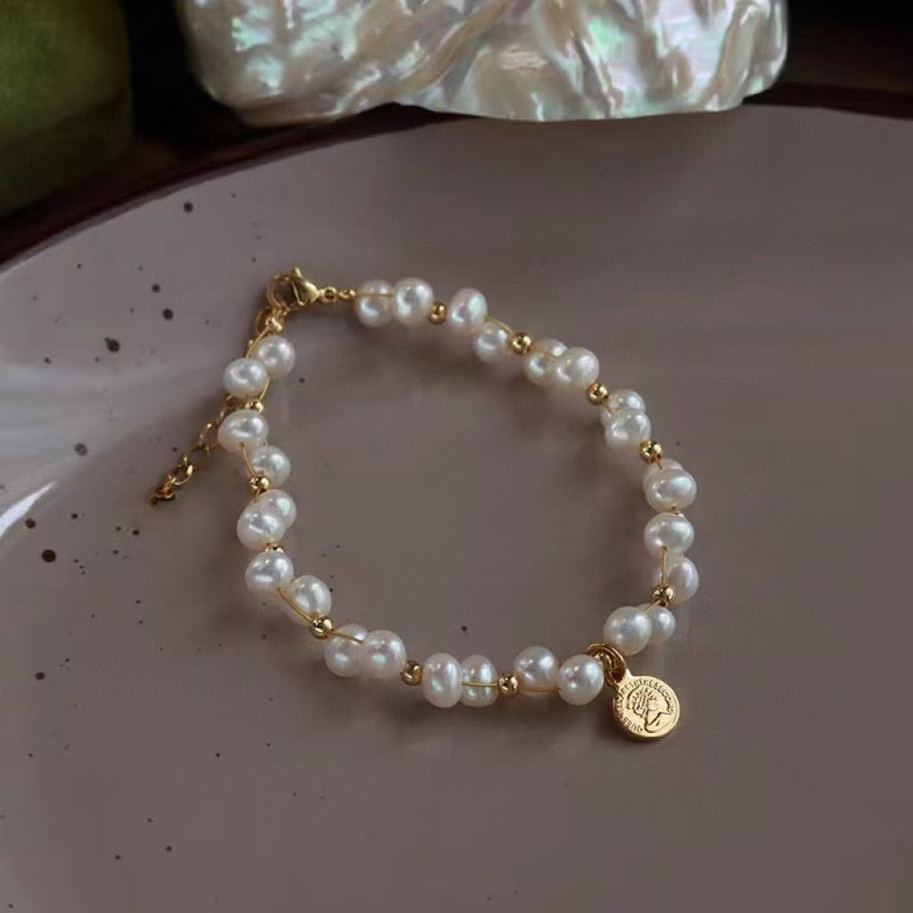 Minimalist freshwater pearl bracelet with round charm and adjustable Japanese woven cord.