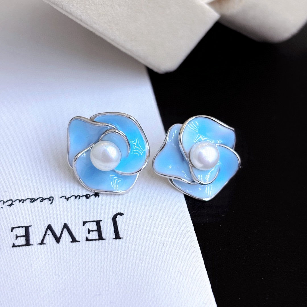 Blue enamel camellia stud earrings with a central freshwater pearl on sterling silver posts.