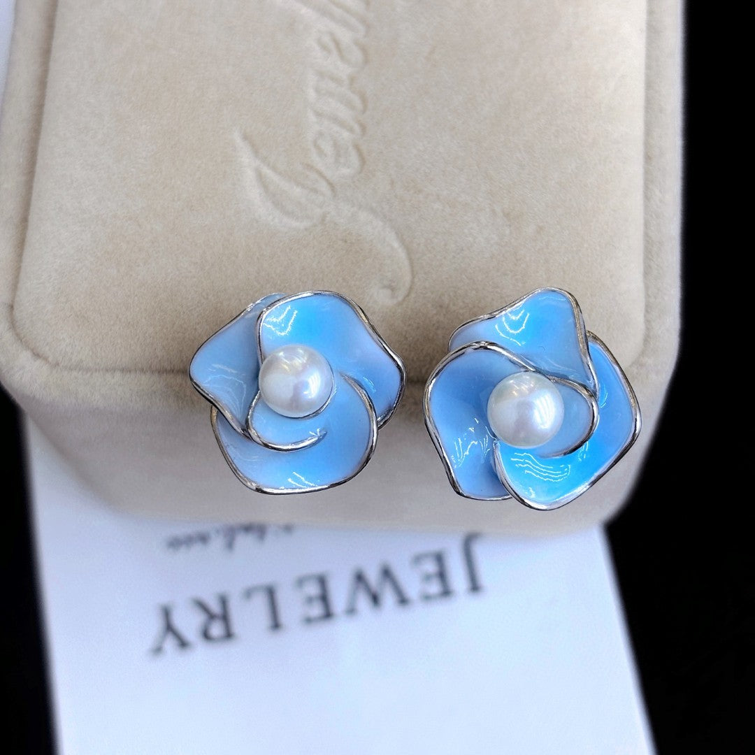 Blue enamel camellia stud earrings with a central freshwater pearl on sterling silver posts.