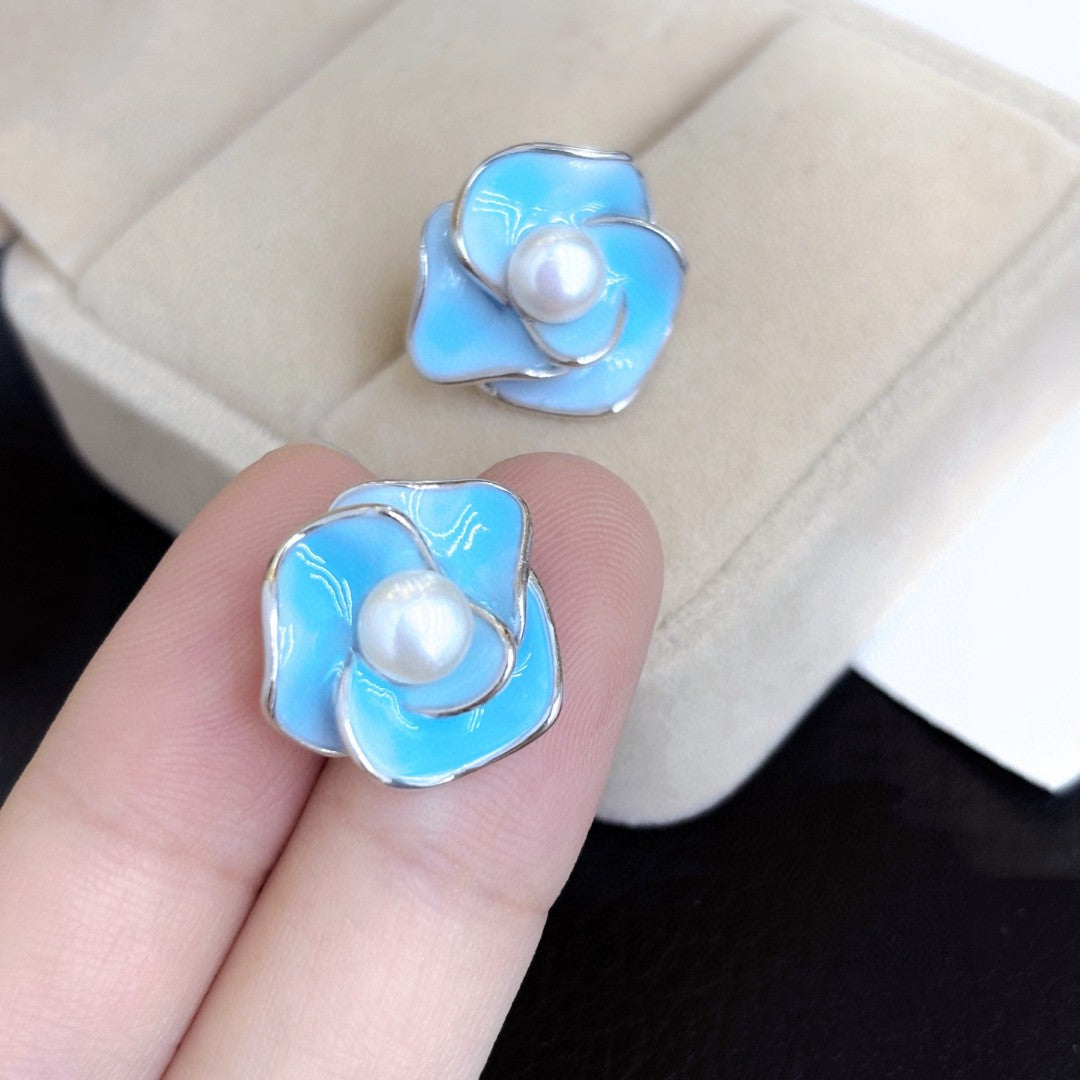 Blue enamel camellia stud earrings with a central freshwater pearl on sterling silver posts.