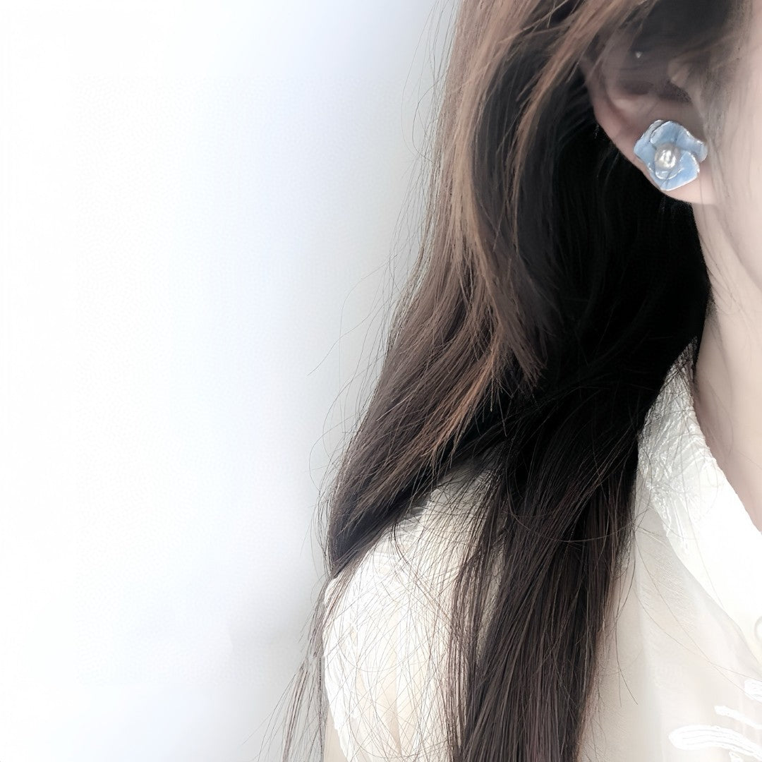 Blue enamel camellia stud earrings with a central freshwater pearl on sterling silver posts.
