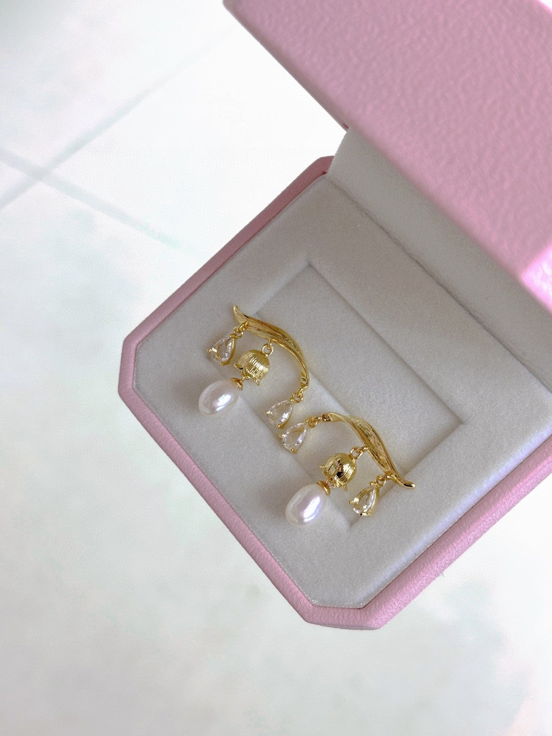 A pair of Chinese-inspired lily-of-the-valley pearl earrings featuring dangling freshwater pearls and intricate silver floral design.