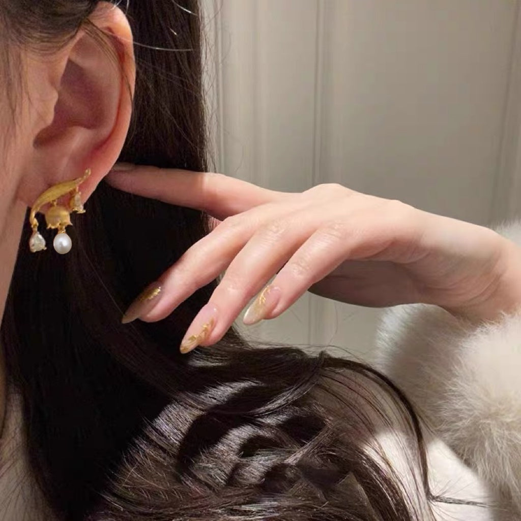 A pair of Chinese-inspired lily-of-the-valley pearl earrings featuring dangling freshwater pearls and intricate silver floral design.