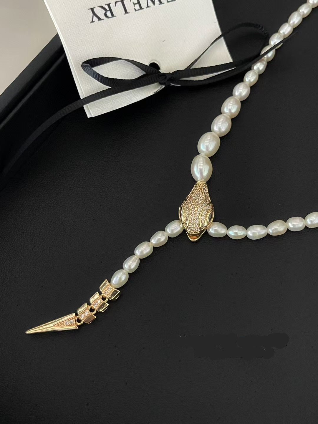 Elegant snake-inspired pearl necklace with cubic zirconia and gradient freshwater pearls.
