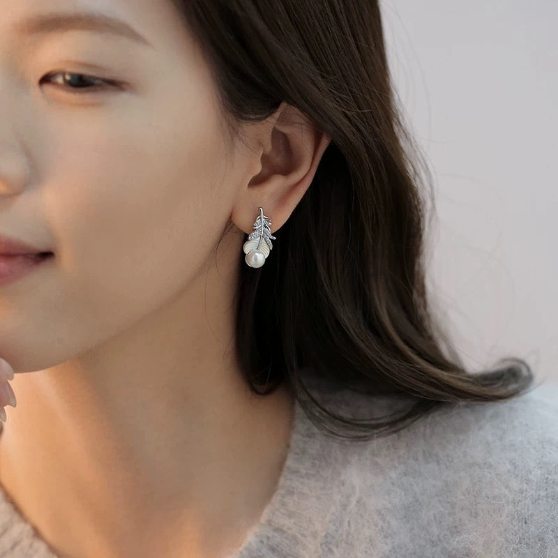 Close-up of feather-inspired pearl earrings
Pearl stud with feather detail and mother-of-pearl finish