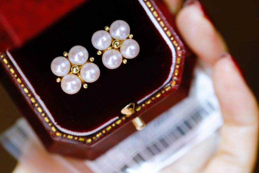 Close-up of four-leaf clover earrings with small freshwater pearls
