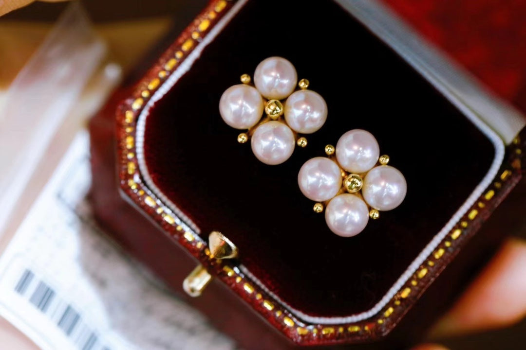 Close-up of four-leaf clover earrings with small freshwater pearls