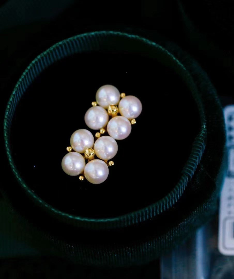 Close-up of four-leaf clover earrings with small freshwater pearls
