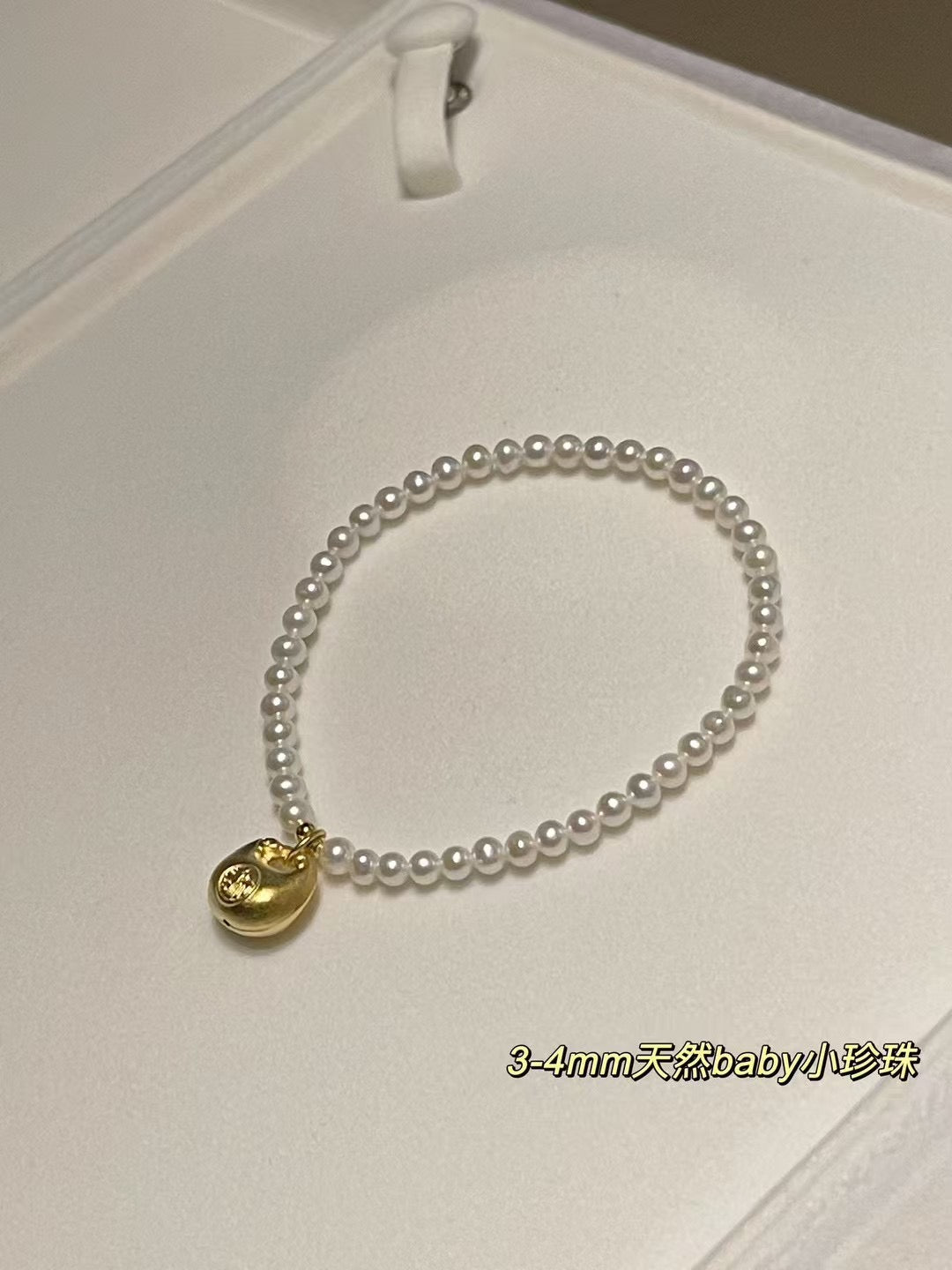 Lucky gold charm pearl bracelet with 3-4mm freshwater pearls and a fortune pouch bead on stretch cord, approx. 17cm length