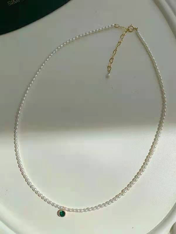 Close-up of seed pearl strand with single green crystal detail