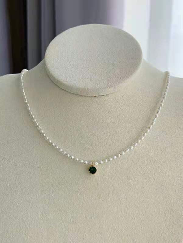 Close-up of seed pearl strand with single green crystal detail
