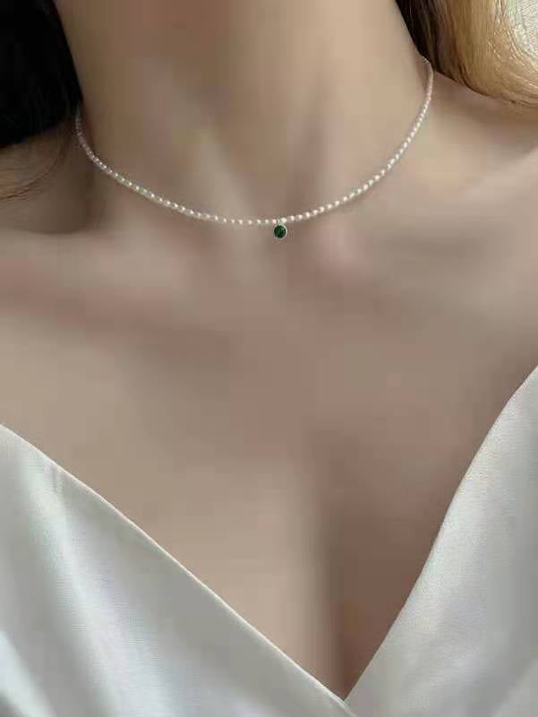 Model wearing chic minimalist pearl necklace with green accent