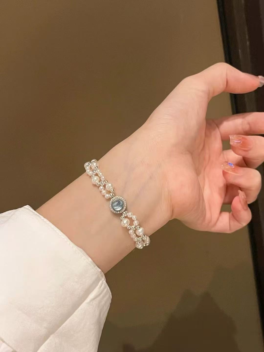 Model wearing ocean-inspired pearl and aquamarine bracelet