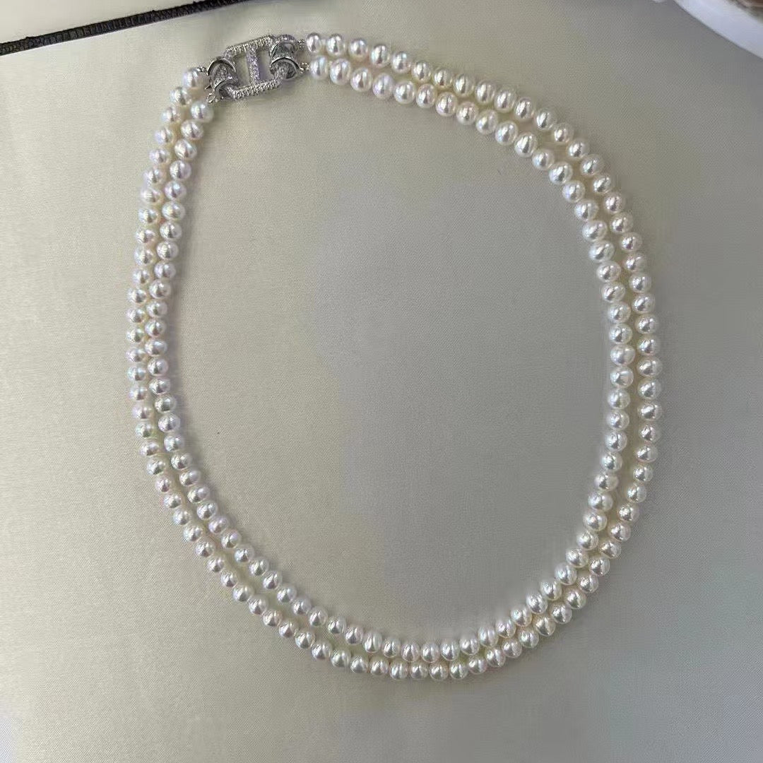 Double-layer pearl choker with gold and zircon clasp on white background