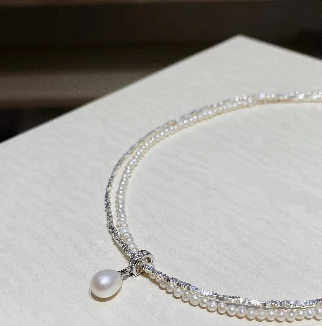 Double-layer sterling silver necklace with baby pearls and teardrop pearl on white background