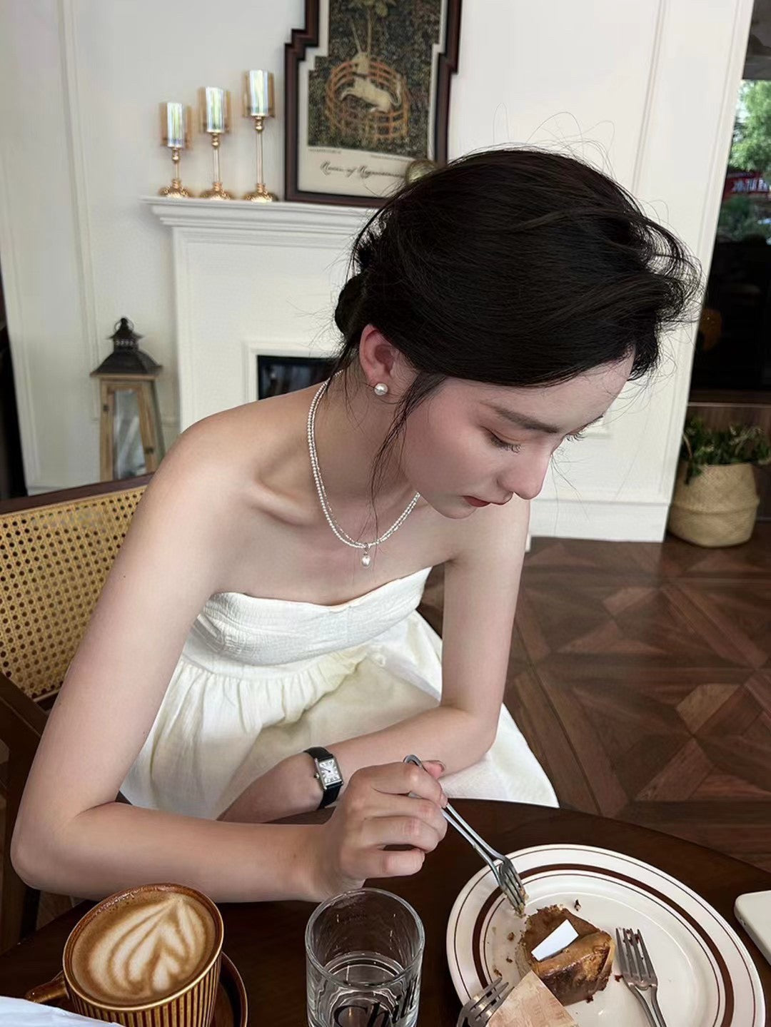 Model wearing layered silver and pearl necklace with soft glow