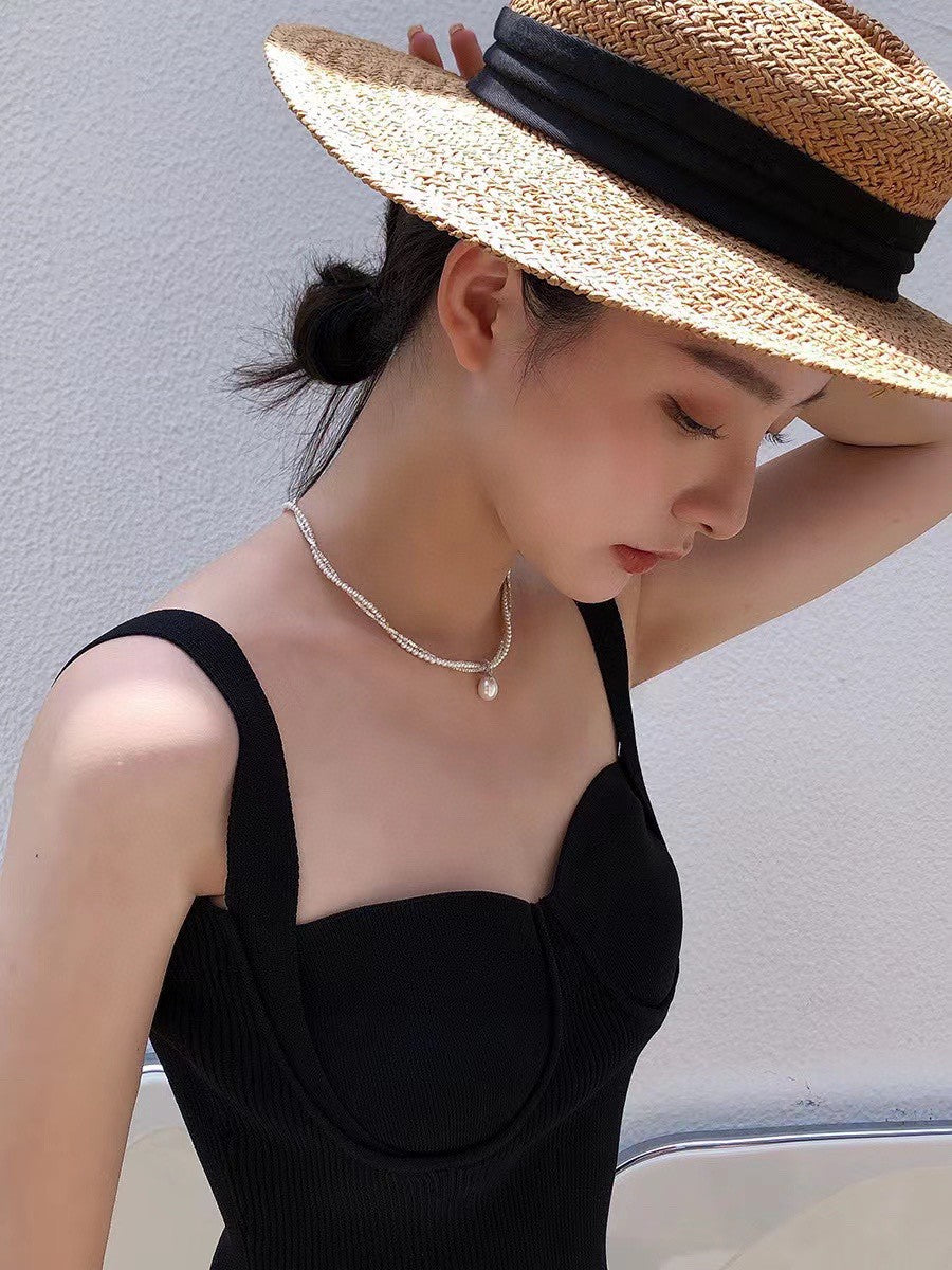 Model wearing layered silver and pearl necklace with soft glow