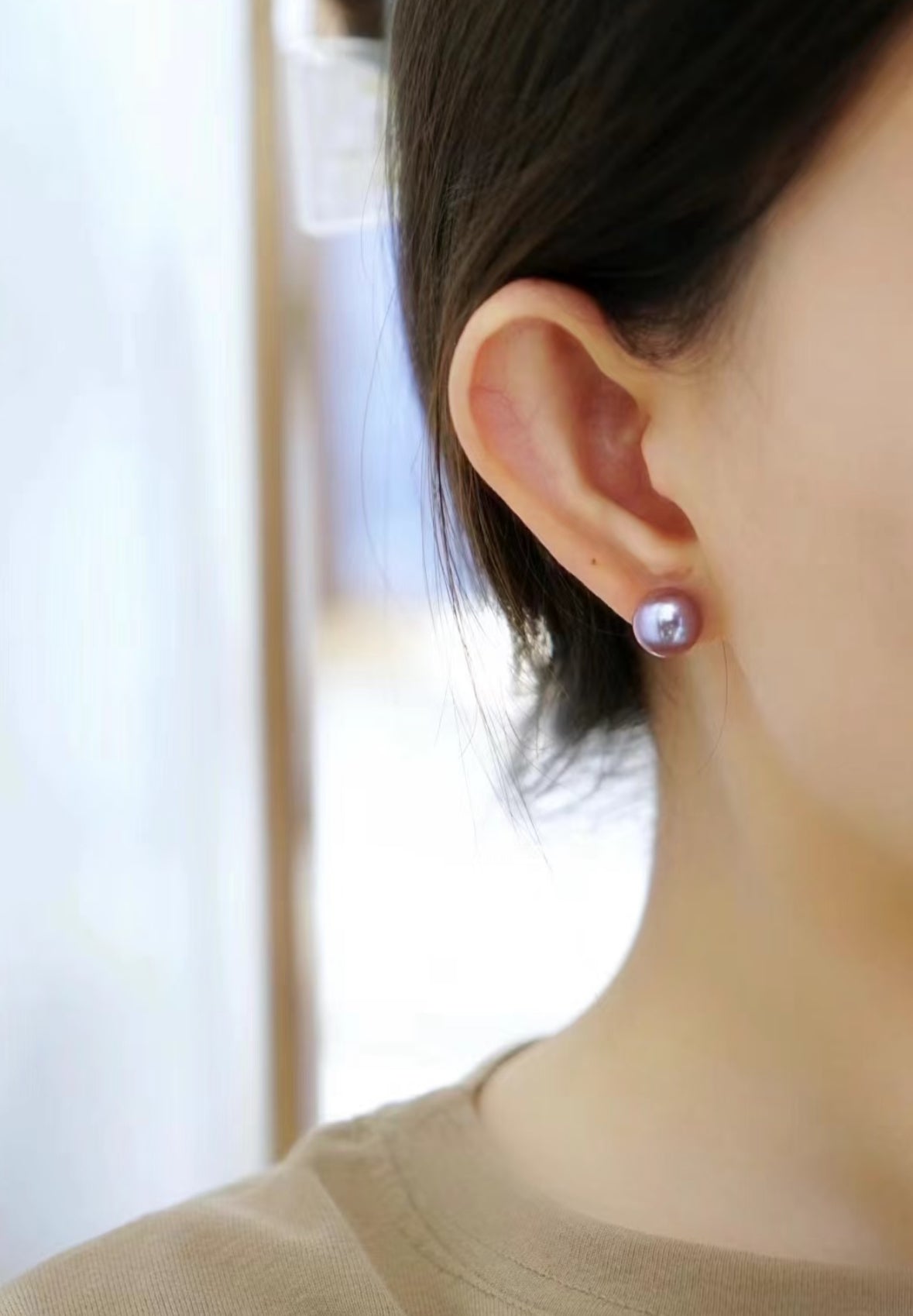 Close-up of 8–9mm lavender freshwater button pearl stud earrings on a white velvet tray