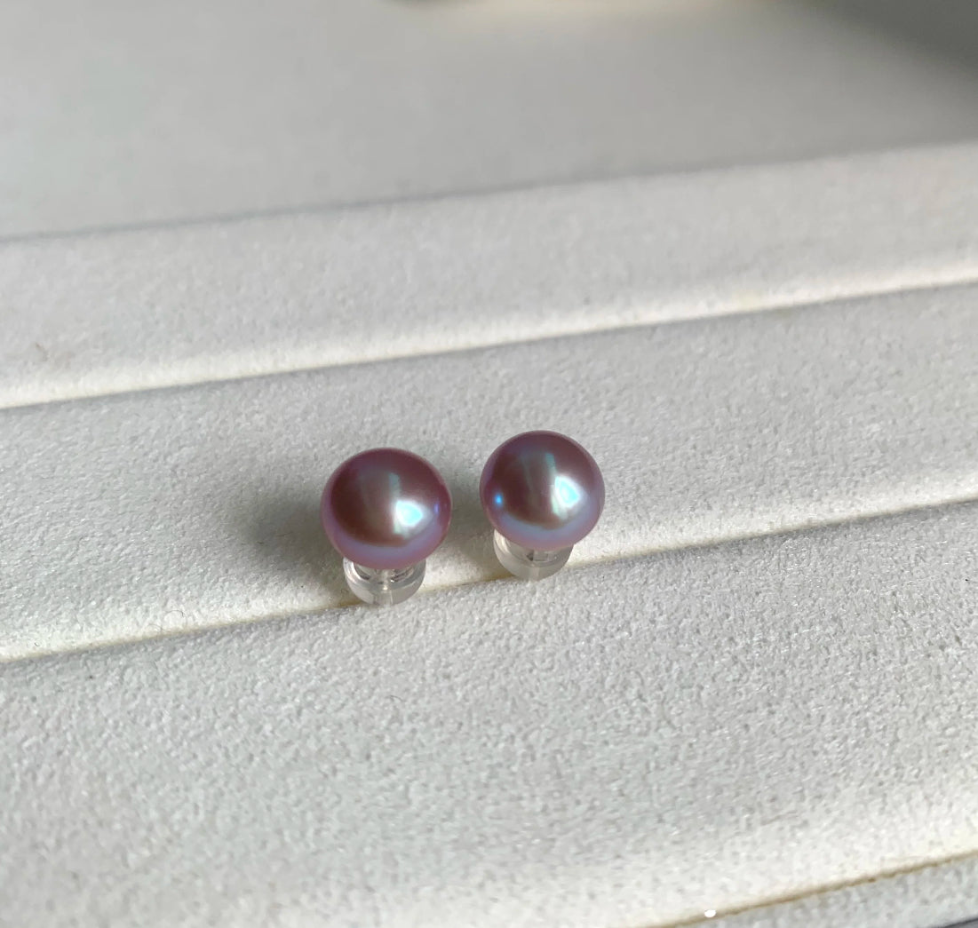 Close-up of 8–9mm lavender freshwater button pearl stud earrings on a white velvet tray
