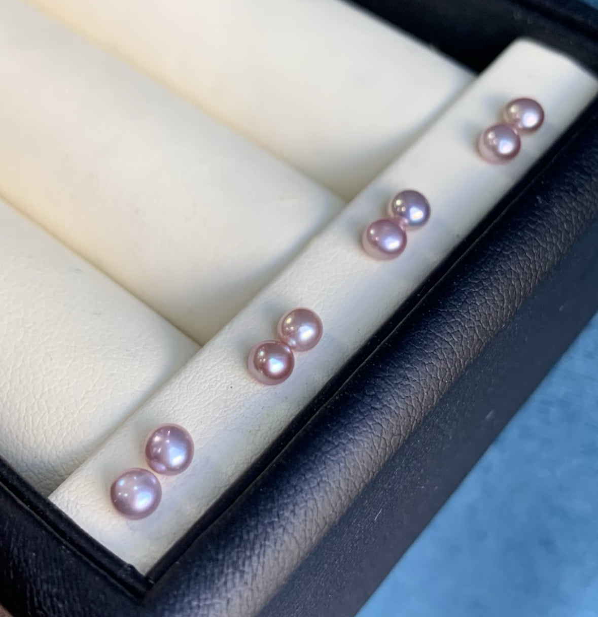 Close-up of 8–9mm lavender freshwater button pearl stud earrings on a white velvet tray