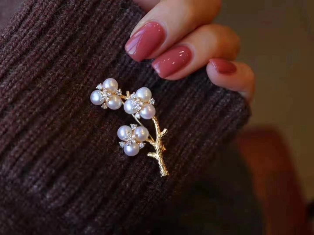 Gold-plated brooch inspired by Chinese plum blossom design with white freshwater pearls, symbolizing elegance and tradition.