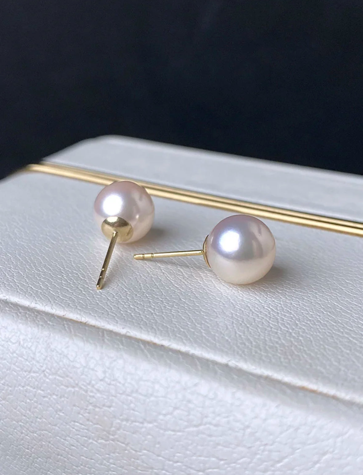 Close-up of luminous Akoya pearl stud earrings set in 18K gold