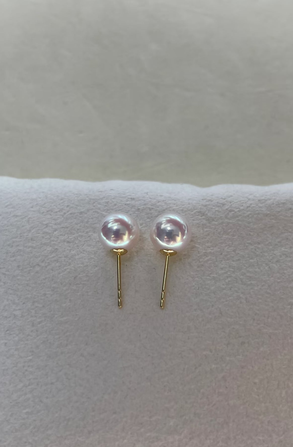 Close-up of luminous Akoya pearl stud earrings set in 18K gold