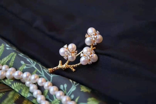Gold-plated brooch inspired by Chinese plum blossom design with white freshwater pearls, symbolizing elegance and tradition.