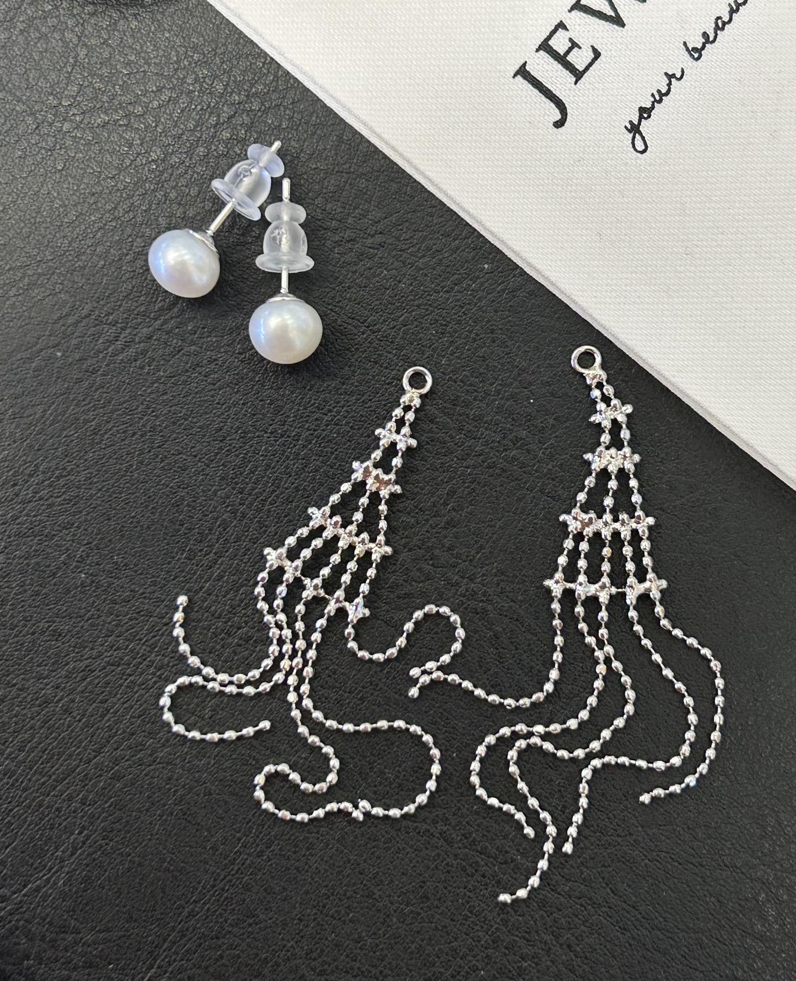 Asymmetric tassel earrings with 7–8mm freshwater pearls and sterling silver posts, featuring a dewdrop-inspired flowing design.