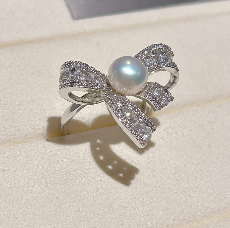Elegant butterfly-shaped ring with zircon inlay and freshwater pearl on an adjustable gold band.