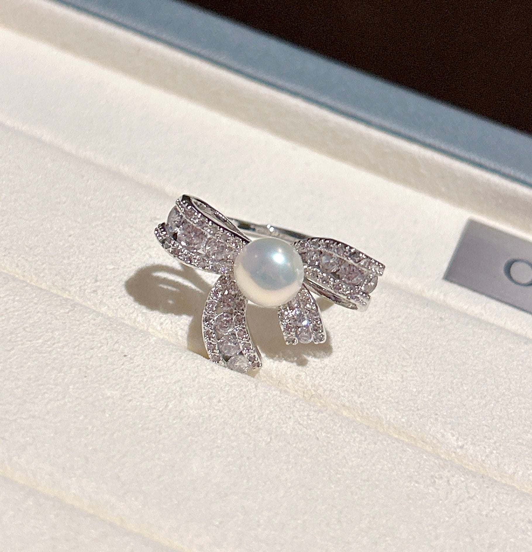 Elegant butterfly-shaped ring with zircon inlay and freshwater pearl on an adjustable gold band.