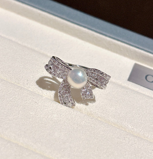 Elegant butterfly-shaped ring with zircon inlay and freshwater pearl on an adjustable gold band.