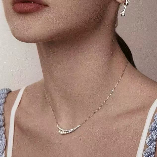 Crescent moon pendant necklace with gradient freshwater pearls in a soft, elegant arrangement.